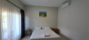 a bedroom with a white bed and a window at Village Corner Homestay in Kuta Lombok