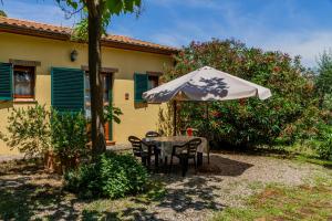 einen Tisch und Stühle unter einem Regenschirm im Hof in der Unterkunft Oleandro - Agriturismo La Fattoria in Grosseto