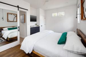 una camera bianca con un grande letto e uno specchio di The Station by Compo Hotels a Travelers Rest