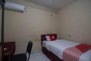 ein Schlafzimmer mit 2 Betten und einem Stuhl darin in der Unterkunft OYO 92714 Miracle Kost in Manado