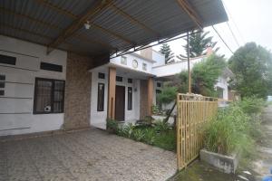 ein Haus mit Markise und einem Tor davor in der Unterkunft OYO 92714 Miracle Kost in Manado