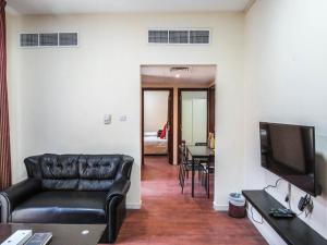 a living room with a couch and a flat screen tv at Al Ferdous Hotel Apartment in Sharjah