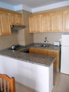 a kitchen with wooden cabinets and a white refrigerator at Apartment in Las Americas in Playa de las Americas