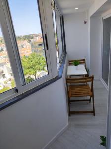 Zimmer mit 2 Fenstern, einem Tisch und einer Bank in der Unterkunft Vista Panorâmica Amadora in Amadora