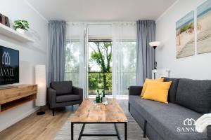 uma sala de estar com um sofá e uma mesa em Apartament River Side - Marina Dziwnów em Dziwnów