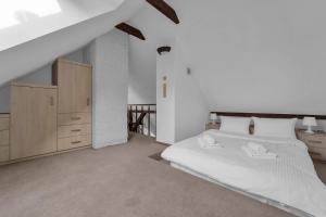 a bedroom with a white bed and a wooden cabinet at Rynek Nowego Miasta Two-Level Apartment by BookingHost in Warsaw