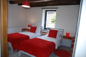 a bedroom with two beds with red sheets and a window at B&B Le Courtil in Dohan