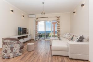 a living room with a white couch and a view of the ocean at apartman 2 in Budva