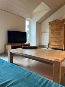 ein Wohnzimmer mit einem Holztisch und einem Flachbild-TV in der Unterkunft Gästehaus beim Metzger / Döttingen am Nürburgring in Döttingen