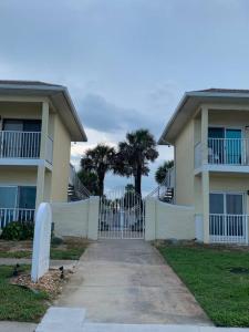 a driveway leading to a house with a gate and palm trees at Ormond Beach, fun & loving sun! in Ormond Beach