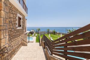 a building with a fence and the ocean in the background at Armonia Seaside Villas in Vasilikos
