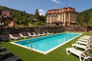 a resort with a pool and chairs and a building at Grand Hotel Pylypets in Pilipets