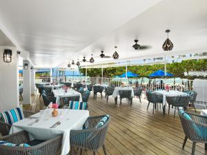 a restaurant with white tables and chairs and blue umbrellas at Coconut Court Beach Hotel in Bridgetown
