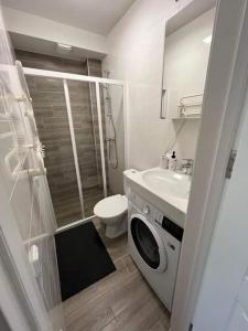 a bathroom with a toilet sink and a washing machine at Modern & cozy studio with patio “Prie Juros” in Palanga