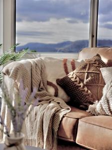 a couch with pillows on it with a large window at Modern holiday home in Hobart - Stunning Mountain & Water views in Rosetta