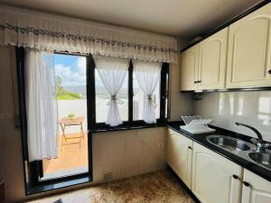 eine Küche mit einem Waschbecken und ein Fenster mit Aussicht in der Unterkunft Gran apartamento completo con terraza en O Barqueiro in O Barqueiro
