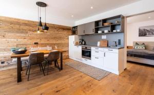 a kitchen and dining room with a wooden wall at Luxus Design Chalet Sonnrain in Piesendorf