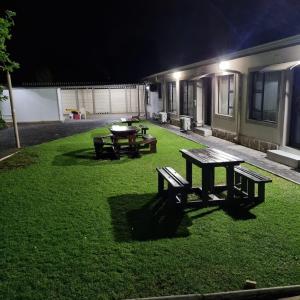 a yard with a picnic table and benches at night at Masechaba guesthouse in Vanderbijlpark