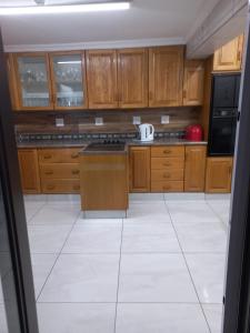 a kitchen with wooden cabinets and a white tile floor at Masechaba guesthouse in Vanderbijlpark