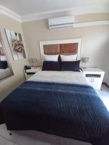 a bedroom with a large blue bed with two tables at Masechaba guesthouse in Vanderbijlpark