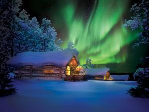 an aurora over a log cabin in the snow at Utsjoki Arctic Resort in Utsjoki