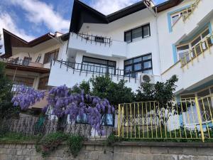 una casa blanca con flores púrpuras detrás de una valla en WHİTE HOUSE en Trebisonda