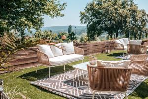 eine Terrasse mit Korbstühlen und einem Tisch auf dem Gras in der Unterkunft Hôtel Le Romantica in Pennedepie