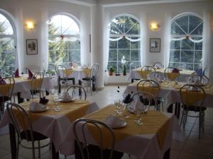 a dining room with tables and chairs and windows at Pension Casa Olga in Paraul Rece