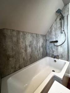 y baño con bañera y pared de hormigón. en Roslin Templar loft, en Roslin