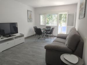 uma sala de estar com um sofá, uma televisão e uma mesa em Apartamento Pie de Playa, El Puntal-Villaviciosa em Villaviciosa