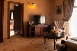 a living room with a couch and a tv and a table at Grand Hotel Pylypets in Pilipets