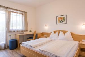 1 dormitorio con cama, escritorio y ventana en Garni Schorneck, en Brunico