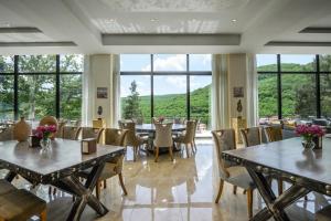 comedor con mesas y sillas y ventanas grandes en Aurora Resort by Stellar Hotels, Tsaghkadzor, en Tsaghkadzor
