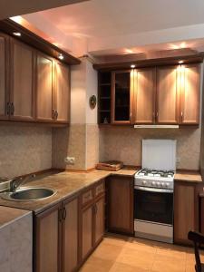 una cucina con mobili in legno, un lavello e una stufa di Rustaveli Ave Apartment a Batumi