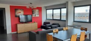 Appart’hôtel Hevea في فالنسيا: غرفة معيشة مع تلفزيون وطاولة وكراسي