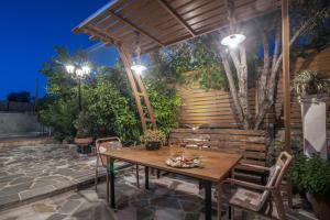 un patio con una mesa de madera y sillas bajo una pérgola en Zamor Family Villa 2, en Zakynthos