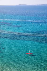 a person sitting on a red surfboard in the water at Hôtel Le Bailli De Suffren in Rayol-Canadel-sur-Mer