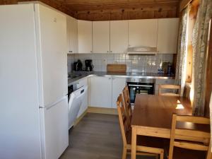 a kitchen with white cabinets and a wooden table at Fanafjorden Cabins in Bergen