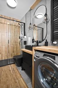uma casa de banho com uma máquina de lavar roupa e um espelho. em Exclusive Apartments with Private Parking and a Gym na Cracóvia