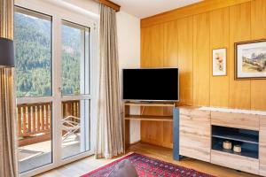 ein Wohnzimmer mit einem TV und einem großen Fenster in der Unterkunft Salman in St. Ulrich in Gröden