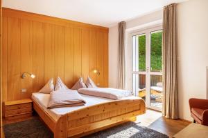 ein Schlafzimmer mit einem Bett mit einer Holzwand in der Unterkunft Salman in St. Ulrich in Gröden