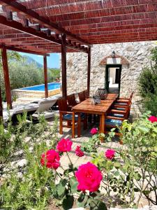 a patio with a wooden table and chairs and flowers at Villa Sagosde with Swimming Pool and Mini Golf in Zagvozd