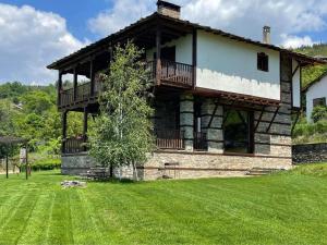 a large house with a balcony on a grass field at Leshten Guest Homes in Leshten