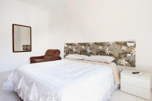 1 dormitorio blanco con 1 cama grande y 1 silla en casa Simona, en Catania
