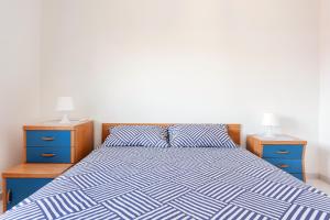 1 cama con edredón azul y blanco y 2 mesitas de noche en casa Simona en Catania
