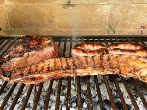 a steak and two sausages on a grill at Departamento con Vista a los cerros con Asador in Yerba Buena