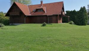 una casa con techo rojo en un campo verde en Álmos Apartman, en Balatonfenyves