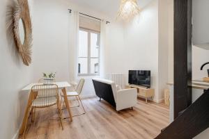 a living room with a table and chairs and a television at  Le Bohème superbe Loft fonctionnel et central in Saint-Étienne