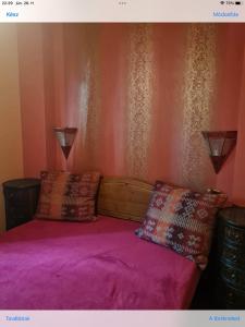 a bedroom with a bed with purple sheets and pillows at Diana Apartman in Balatonszepezd