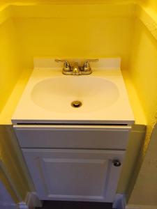 a bathroom sink with a faucet on a yellow wall at Aldrich Hotel in San Francisco